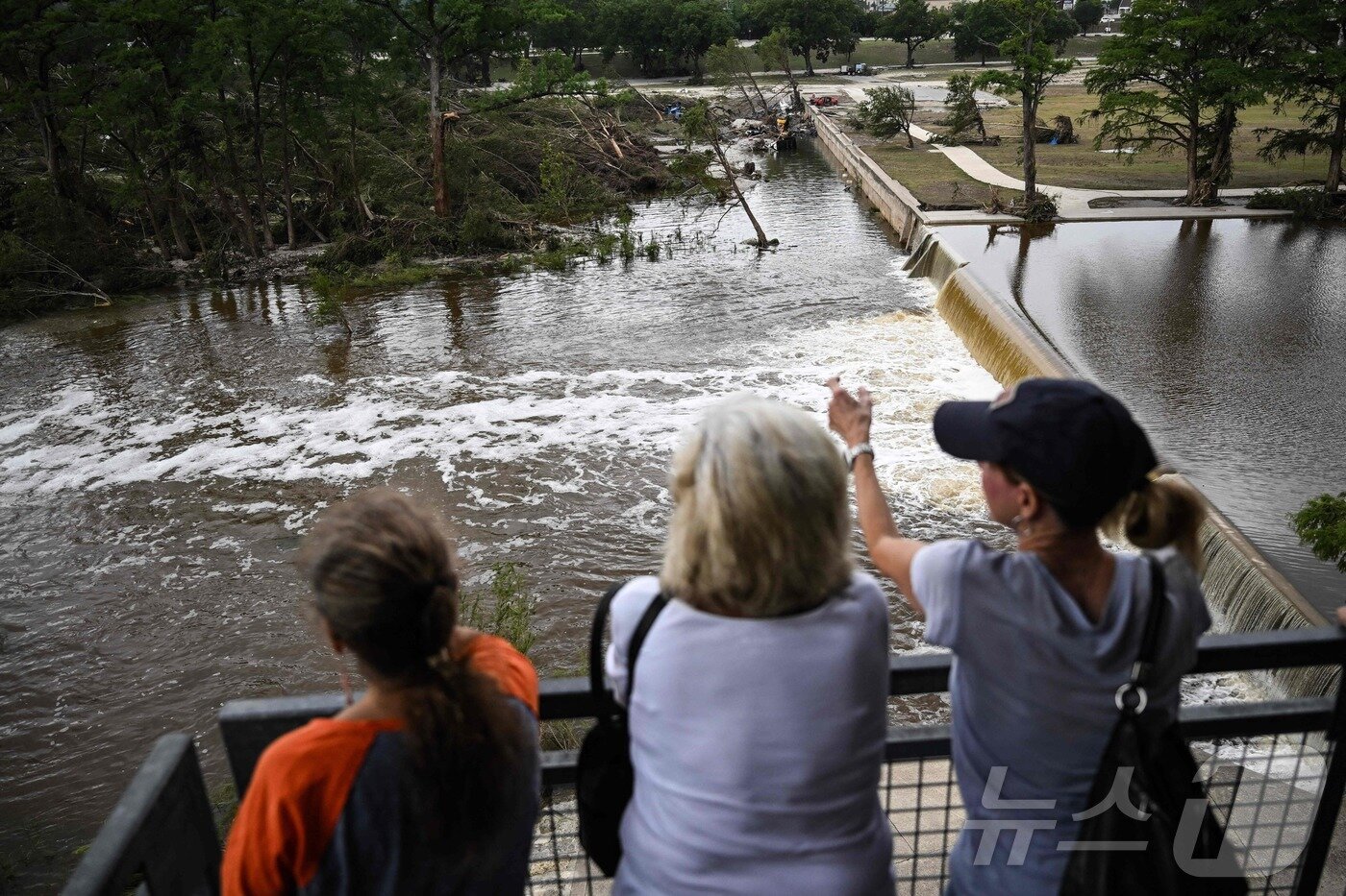 본문 이미지 - 6일(현지시간) 미국 텍사스주 커빌의 과달루페 강에서 시민들이 걱정스러운 표정으로 불어나는 물 수위를 지코보고 있다. ⓒ AFP=뉴스1
