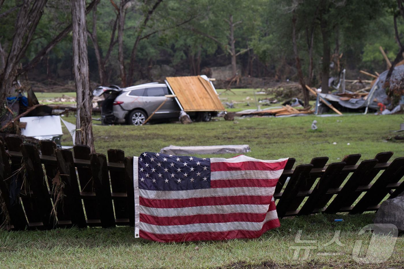 본문 이미지 - 6일(현지시간) 미국 텍사스 헌트의 홍수 피해 지역 잔해 속에 미국 국기가 걸려 있다. ⓒ AFP=뉴스1