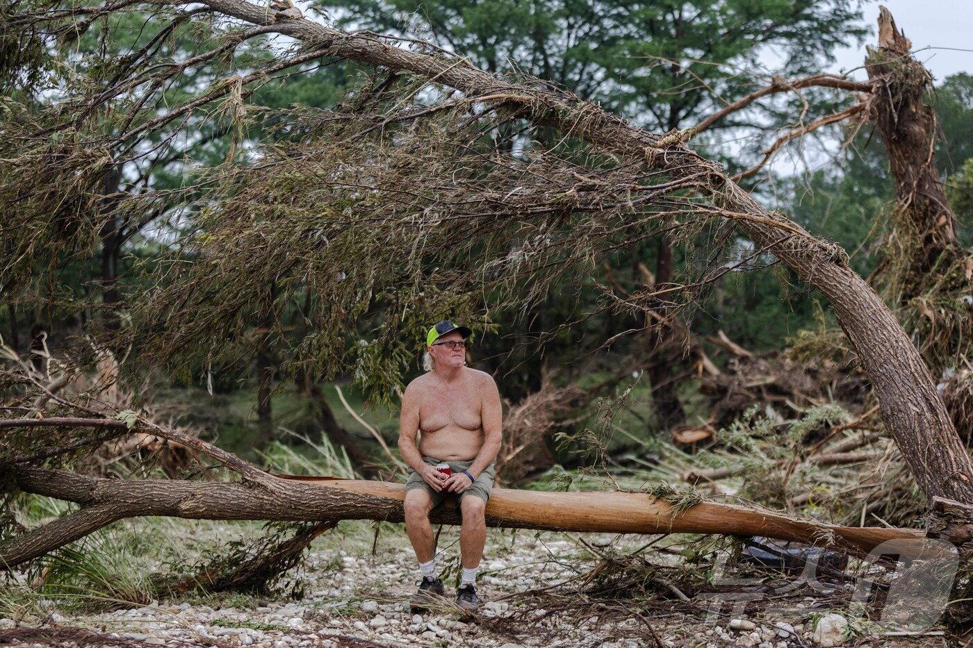 본문 이미지 - 6일(현지시간) 미국 텍사스주  센터 포인트의 과달루페 강둥에서 한 시민이 나무 잔해 위에 황망히 앉아 있다.ⓒ AFP=뉴스1