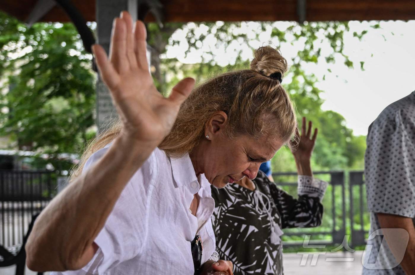 본문 이미지 - 6일(현지시간) 미국 텍사스주 커빌의 과달루페 강 인근에 홍수 피해가 극심한 가운데 시민들이 기도를 하고 있다.ⓒ AFP=뉴스1