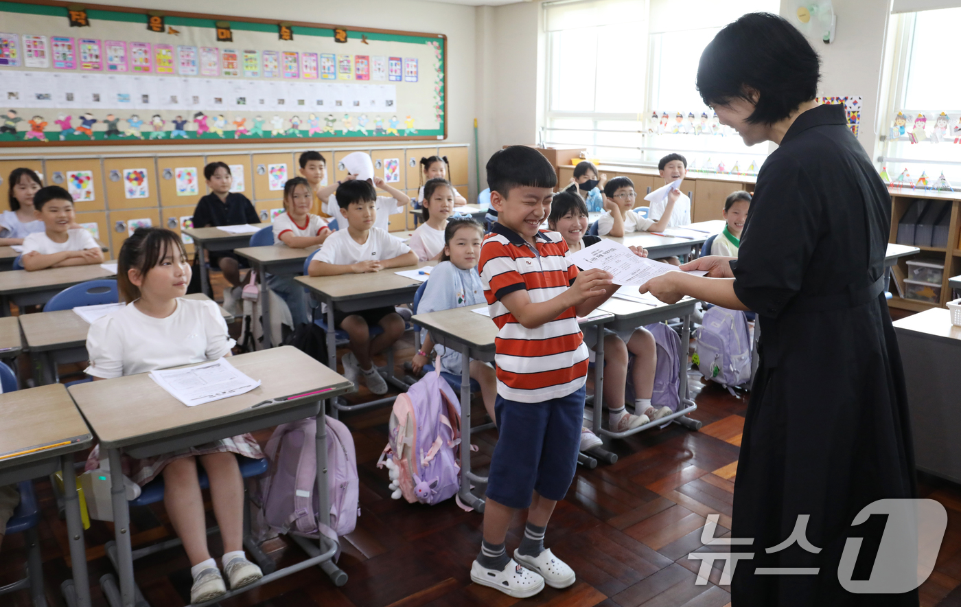 (부산=뉴스1) 윤일지 기자 = 7일 오전 부산 동래구 명륜초등학교에서 여름방학을 맞은 2학년 3반 학생이 선생님에게 방학 계획서를 받으며 환하게 웃고 있다.이 학교는 내부 공사로 …