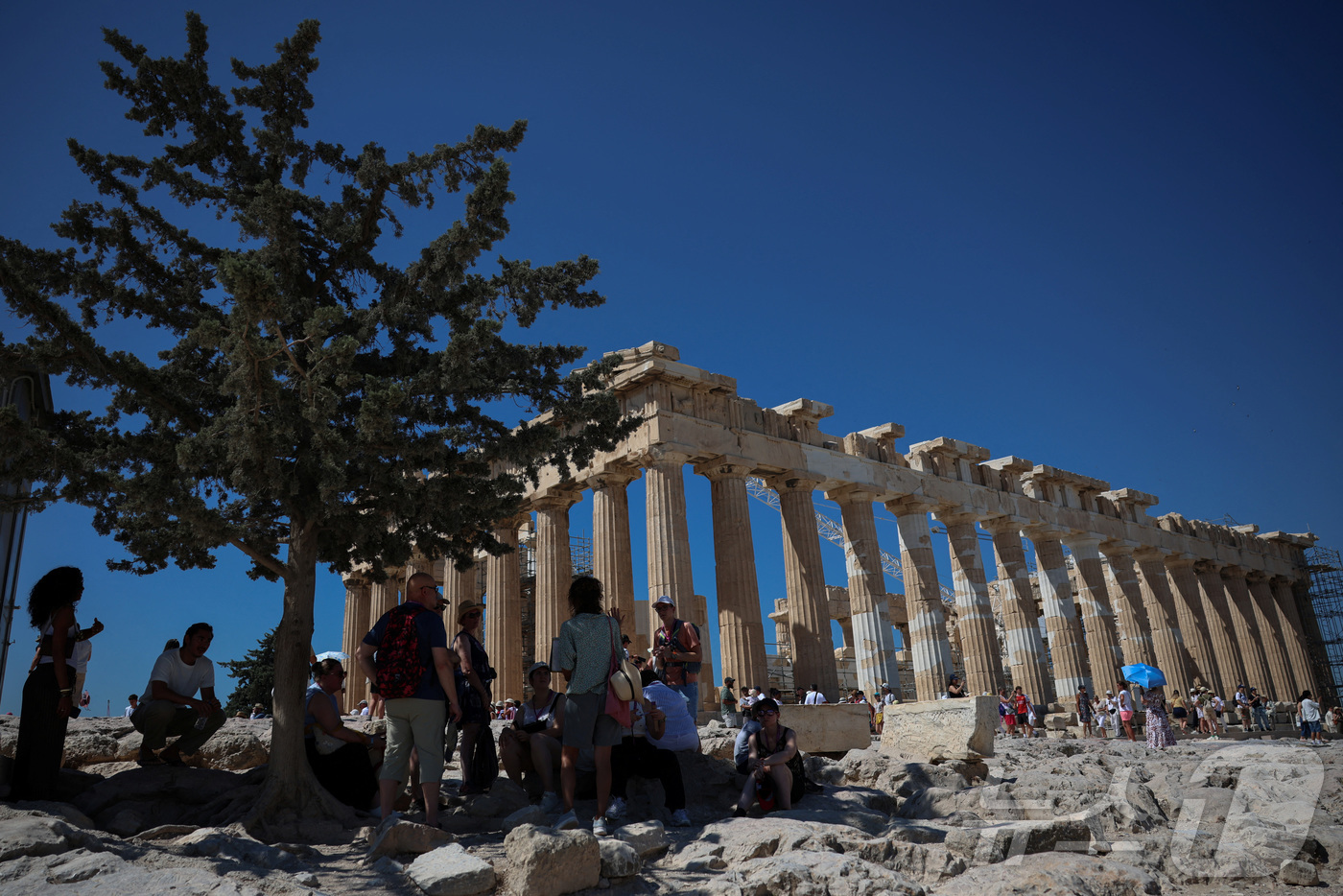 (아테네 로이터=뉴스1) 윤다정 기자 = 7일(현지시간) 그리스 아테네 아크로폴리스를 찾은 관광객들이 더위를 피해 나무 그늘 아래 모여 있다. 2025.07.07.ⓒ 로이터=뉴스1 …