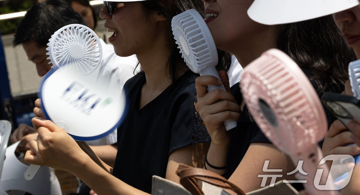 본문 이미지 - 8일 오전 서울 중구 청계광장에서 열린 &#39;K-바캉스 캠페인&#39; 개회식 참석자들이 미니 선풍기와 부채로 더위를 식히고 있다. 한국경제인연합회는 여름 휴가철을 맞아 국내 관광 수요를 확대하고 침체된 지역경제에 활력을 불어넣기 위해 이번 행사를 기획했다고 밝혔다. 2025.7.8/뉴스1 ⓒ News1 이승배 기자