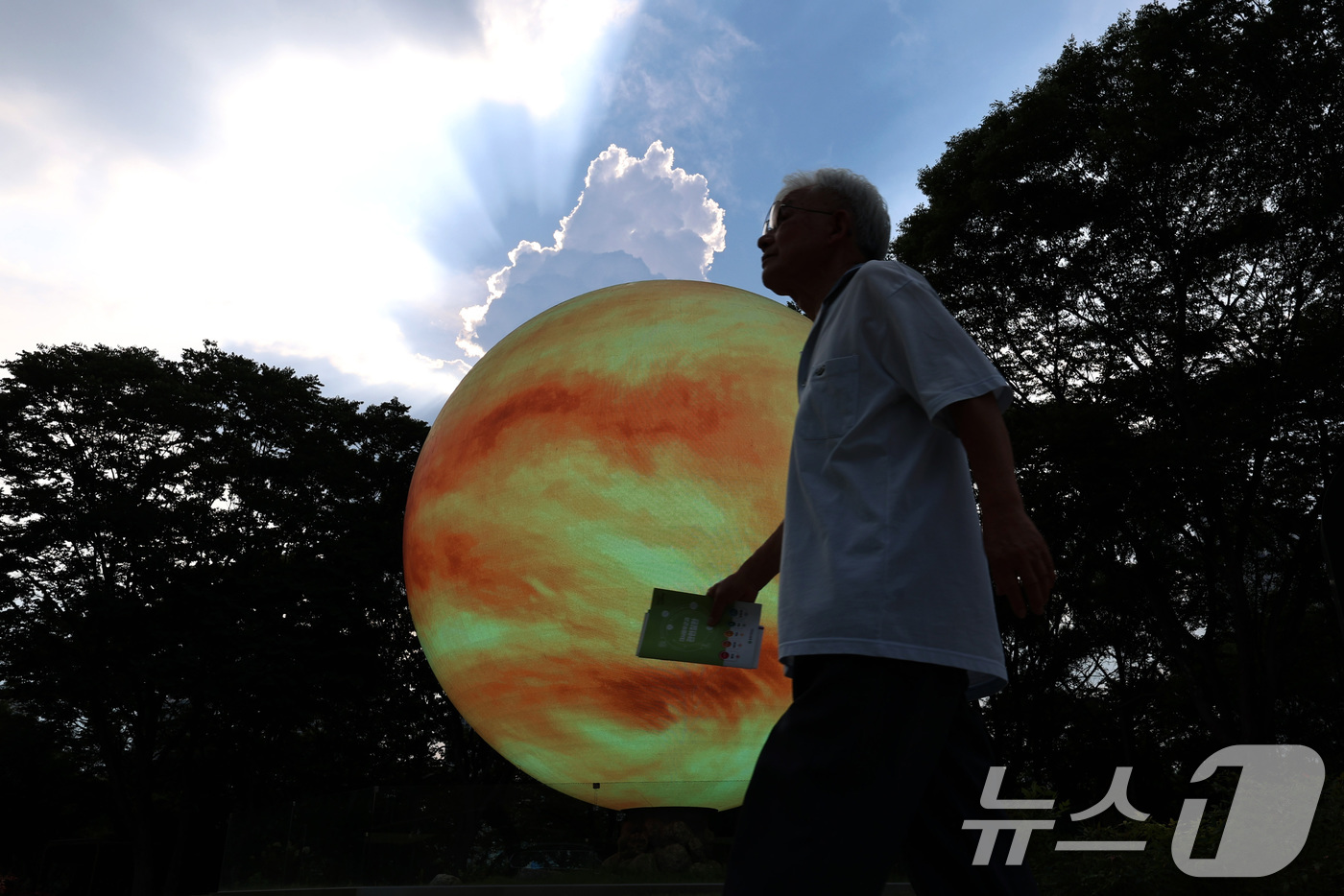 (서울=뉴스1) 구윤성 기자 = 서울의 낮 최고기온이 37도를 기록한 8일 오후 한 시민이 서울 송파구의 조형물 앞을 지나고 있다. 2025.7.8/뉴스1