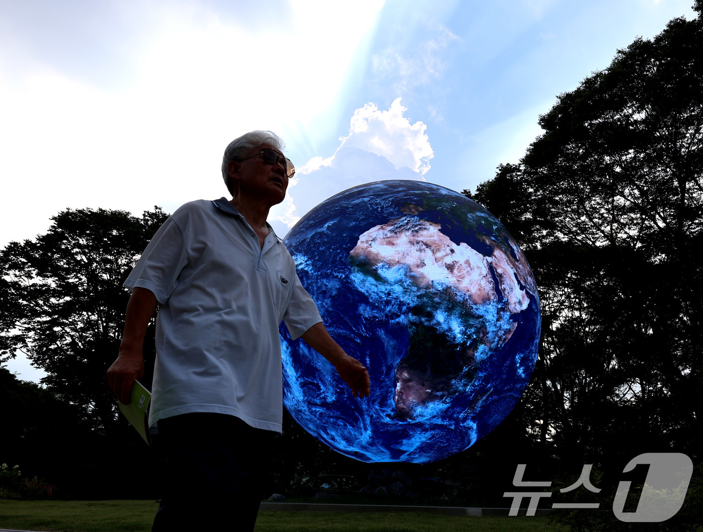 (서울=뉴스1) 구윤성 기자 = 서울의 낮 최고기온이 37도를 기록한 8일 오후 한 시민이 서울 송파구의 조형물 앞을 지나고 있다. 2025.7.8/뉴스1