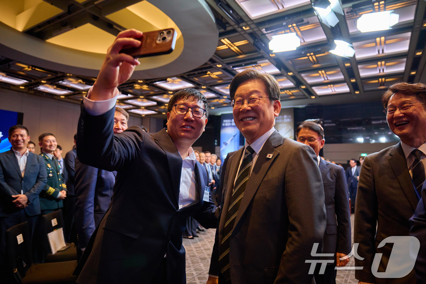 (서울=뉴스1) 허경 기자 = 이재명 대통령이 8일 서울 용산구 그랜드 하얏트 호텔에서 열린 제1회 방위산업의 날 토론회에서 한 참석자와 셀카 촬영을 하고 있다. (대통령실 제공. …