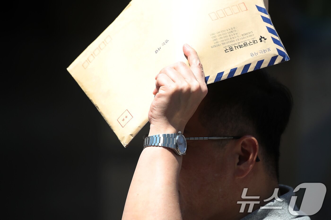 본문 이미지 - 폭염이 계속된 1일 대구 중구 동성로에서 한 시민이 서류 봉투로 뙤약볕을 가린 채 발걸음을 옮기고 있다. 2025.8.1/뉴스1 ⓒ News1 공정식 기자