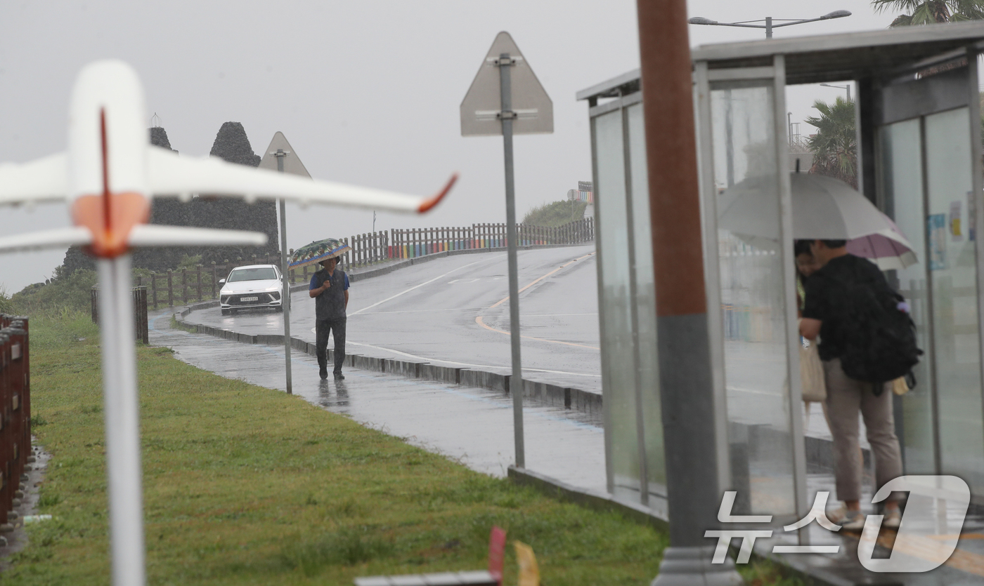 (제주=뉴스1) 오현지 기자 = 제주에 비가 내리면서 폭염특보가 모두 해제된 11일 오전 제주시 용담해안도로에서 우산을 쓴 관광객들이 발걸음을 옮기고 있다. 2025.8.11/뉴스 …