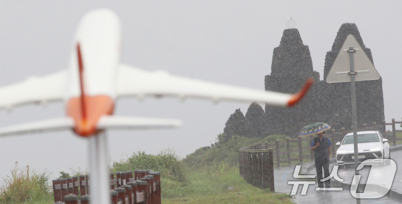 (제주=뉴스1) 오현지 기자 = 제주에 비가 내리면서 폭염특보가 모두 해제된 11일 오전 제주시 용담해안도로에서 우산을 쓴 행인이 발걸음을 옮기고 있다. 2025.8.11/뉴스1