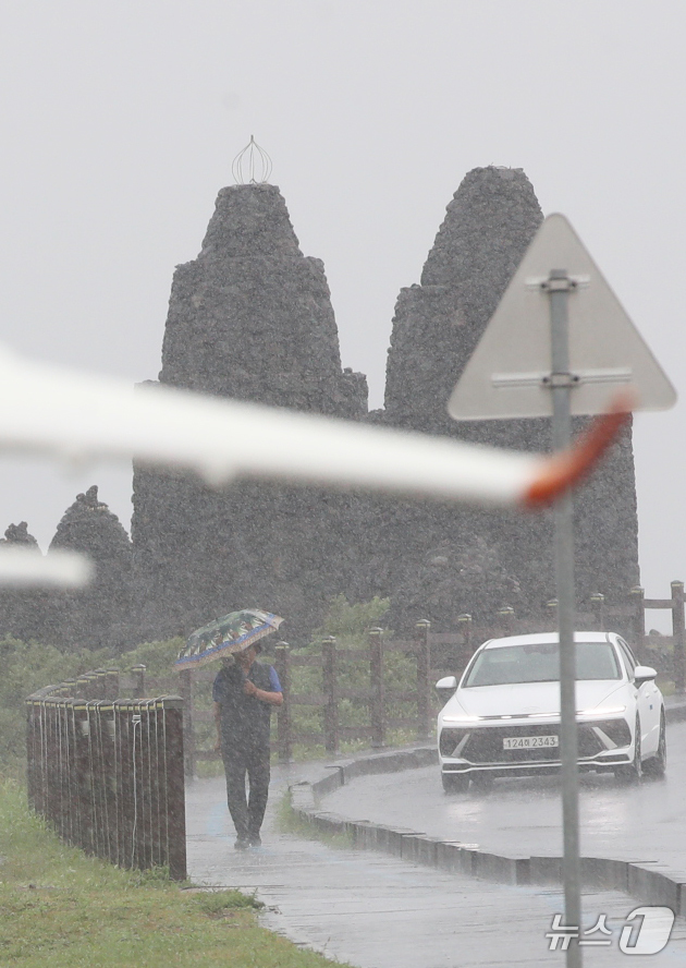 (제주=뉴스1) 오현지 기자 = 제주에 비가 내리면서 폭염특보가 모두 해제된 11일 오전 제주시 용담해안도로에서 우산을 쓴 행인이 발걸음을 옮기고 있다. 2025.8.11/뉴스1