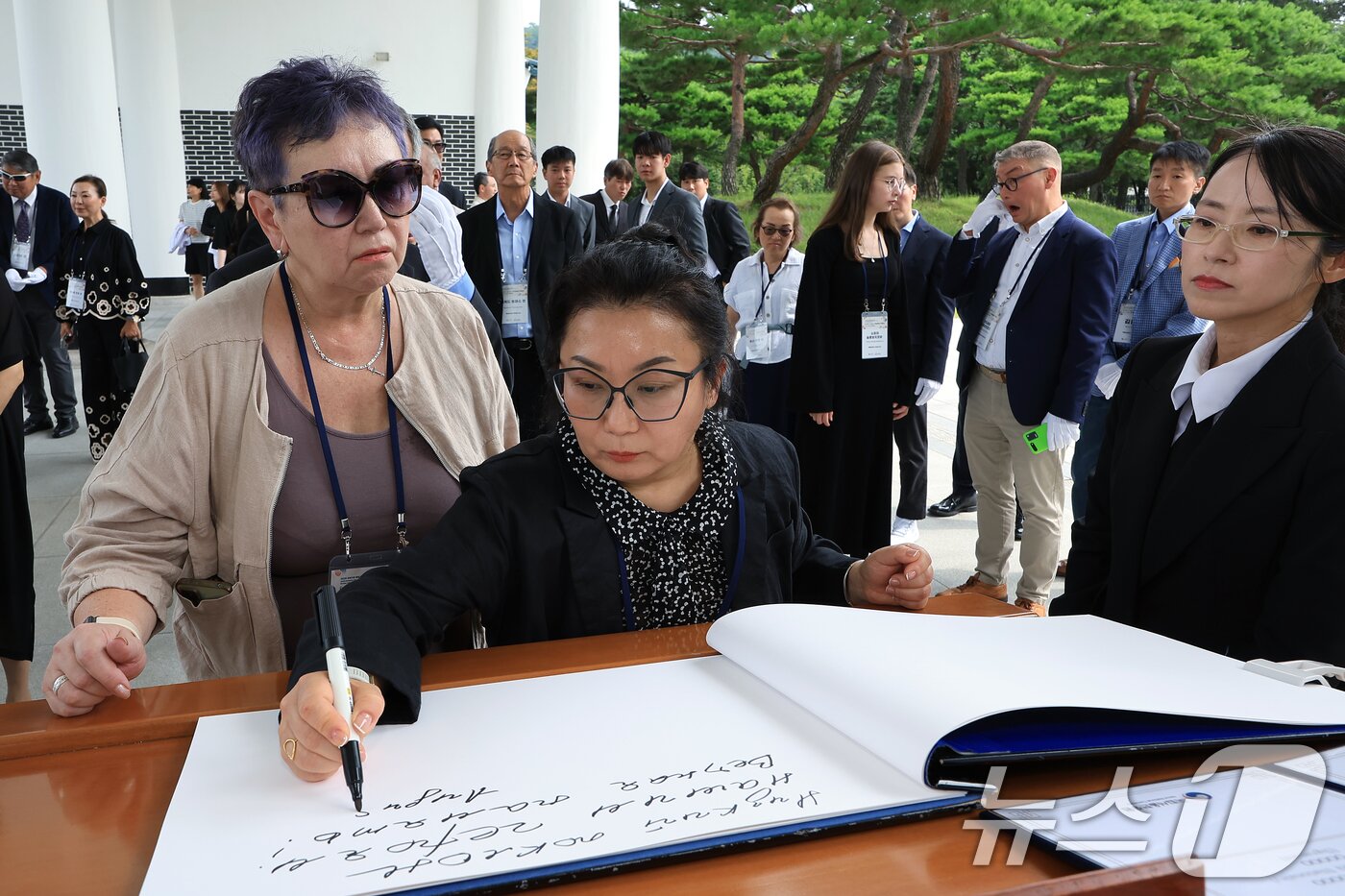 본문 이미지 - 광복 80주년을 맞아 방한한 미국을 비롯한 6개국에 거주 중인 독립유공자 후손 중 신흥무관학교 교관과 수청지역 창해청년단 총사령관 등으로 활약한 김경천 지사&#40;1998년, 대통령장&#41;의 증손인 무사예바 이리나 씨가 11일 오후 서울 동작구 국립서울현충원 현충탑 참배를 마친 뒤 방명록을 남기고 있다. 왼쪽은 연해주 독립운동의 대부로, 한인 동포들에게 큰 사랑을 베풀어 ‘페치카&#40;러시아어로 ’난로‘&#41;’로 불린 최재형 선생&#40;1962, 독립장&#41;의 증손인 강 올가 씨. 2025.8.11/뉴스1 ⓒ News1 박정호 기자