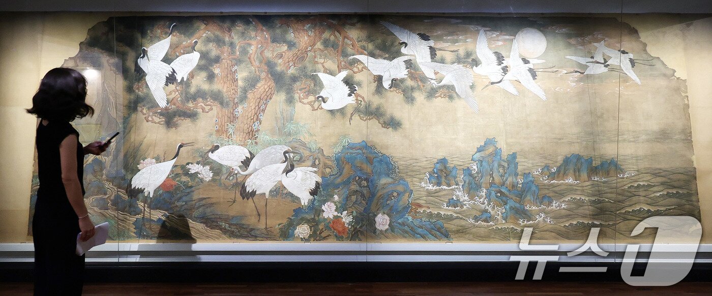 본문 이미지 - 13일 서울 종로구 국립고궁박물관 2층 기획전시실에서 열린 특별전 '창덕궁의 근사謹寫한 벽화' 언론 공개회에서 참석자가 김은호 '백학도'를 살펴보고 있다. 국립고궁박물관은 14일부터 개관 20주년 특별전 '창덕궁의 근사謹寫한 벽화'에서 창덕궁 내전인 희정당, 대조전, 경훈각을 장식했던 벽화 6점을 최초로 일괄 공개한다. 2025.8.13/뉴스1 ⓒ News1 박지혜 기자