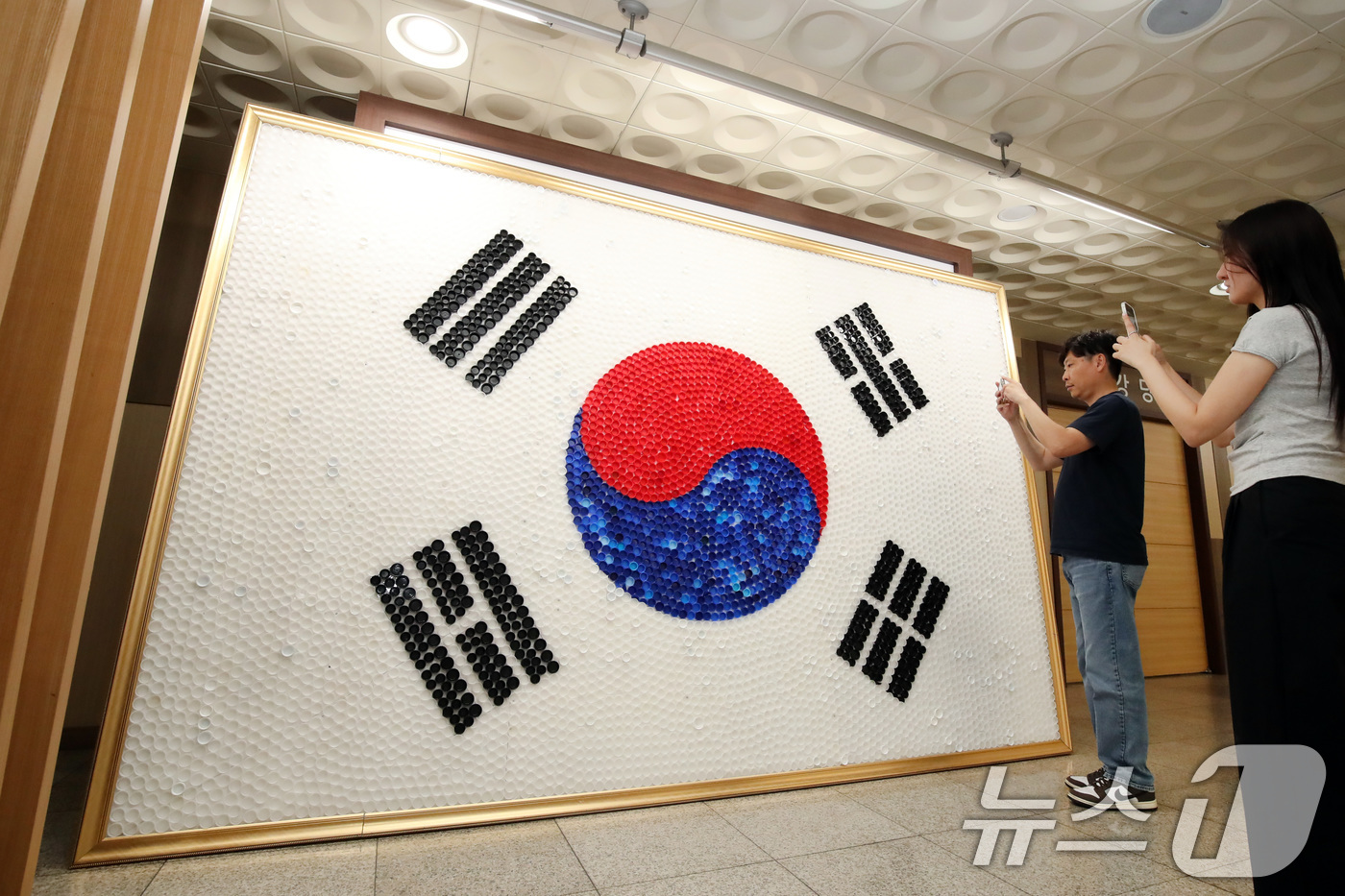 (대구=뉴스1) 공정식 기자 = 80주년 광복절을 이틀 앞둔 13일 대구 달서구청 로비에 달서구노인종합복지관 어르신들이 페트병 뚜껑 6900여 개를 붙여 만든 '생명의 태극기'가 …