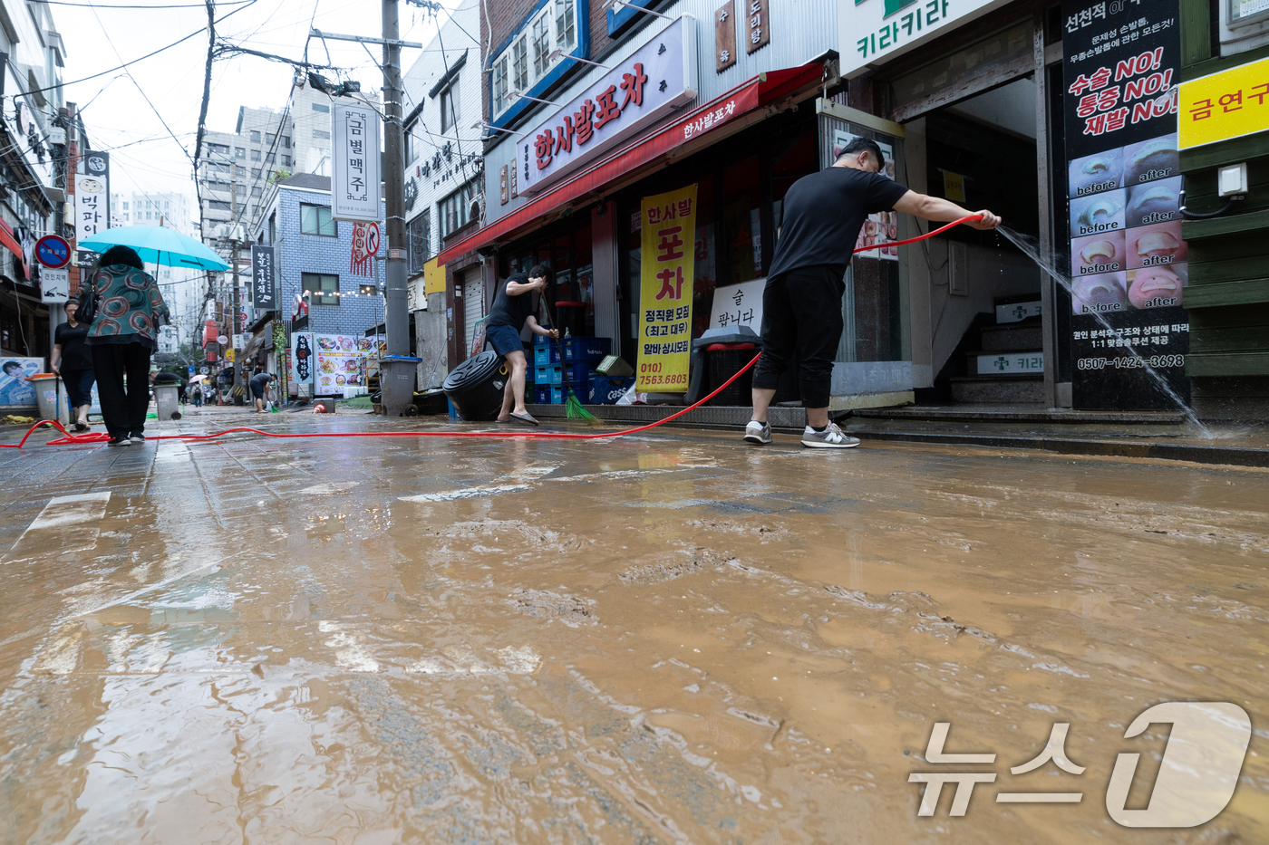 (서울=뉴스1) 이승배 기자 = 13일 오후 서울 은평구 연신내역 인근 상가 거리에서 상인들이 폭우로 인해 더러워진 거리를 청소하고 있다. 2025.8.13/뉴스1