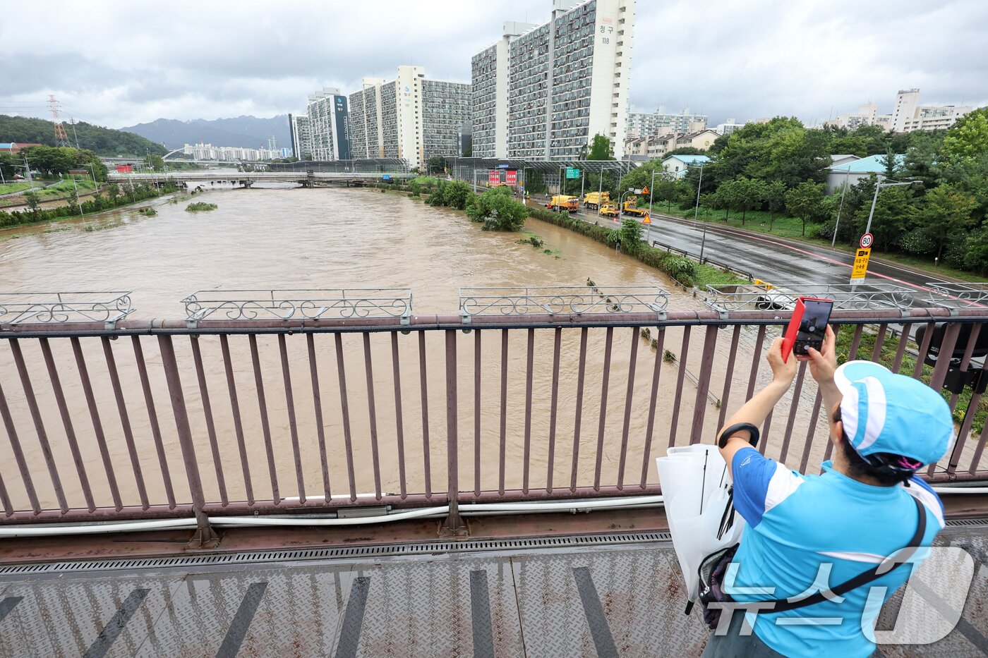 본문 이미지 - 서울 동북·서북권에 호우경보가 발령된 13일 서울 노원구 월계동에서 한 시민이 집중호우에 불어난 중랑천을 스마트폰 카메라에 담고 있다. 2025.8.13/뉴스1 ⓒ News1 민경석 기자