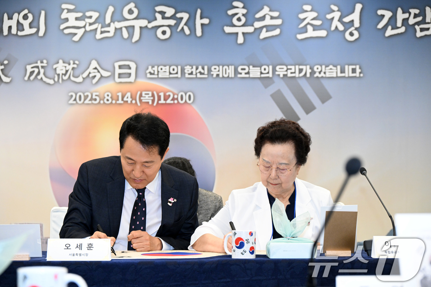 (서울=뉴스1) = 오세훈 서울시장이 14일 서울 중구 서울시청에서 열린 '광복 80주년 경축식'에서 이소심 여사와 태극기에 서명을 하고 있다. (서울시 제공. 재판매 및 DB 금 …