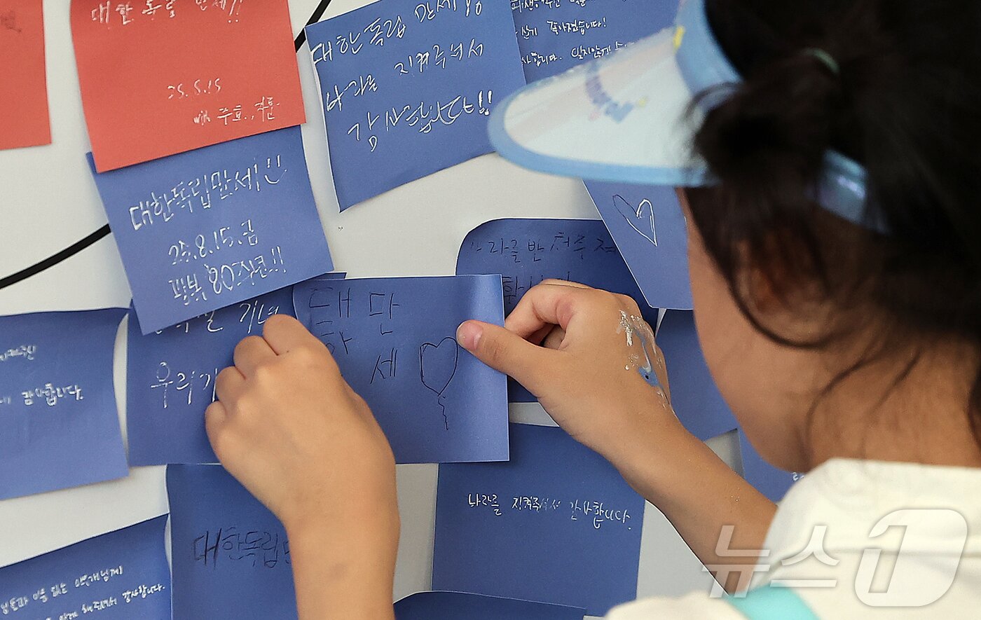 본문 이미지 - 제80주년 광복절인 15일 서울 서대문형무소역사관을 찾은 어린이가 광복절 응원하는 문구를 태극기에 부착하고 있다. 2025.8.15/뉴스1 ⓒ News1 김진환 기자