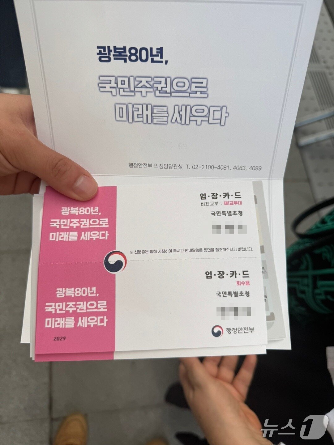 본문 이미지 - 18일 오후 서울 광화문 광장에서 열린 제21대 대통령 국민임명식에 참석한 한 시민이 입장카드를 펼쳐 보이고 있다. 2025.8.15/뉴스1 권준언 기자