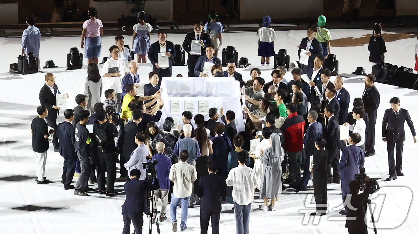 본문 이미지 - 15일 오후 서울 종로구 광화문광장에서 열린 &#39;광복 80년, 국민 주권으로 미래를 세우다&#39; 제21대 대통령 국민 임명식에서 국민 대표 80인이 &#39;이재명 대통령을 임명한다&#39;는 내용을 담은 빛의 임명장을 큐브에 붙이고 있다. 2025.8.15/뉴스1 ⓒ News1 김민지 기자