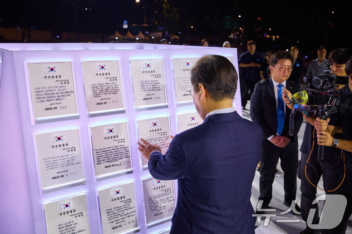 본문 이미지 - 이재명 대통령이 지난 15일 서울 세종대로 광화문광장에서 열린 &#39;광복 80년, 국민 주권으로 미래를 세우다&#39; 제21대 대통령 국민 임명식에서 국민 대표 80인이 참여한 임명장을 보고 있다. &#40;이재명 대통령 SNS. 재판매 및 DB 금지&#41; 2025.8.16/뉴스1 ⓒ News1 허경 기자