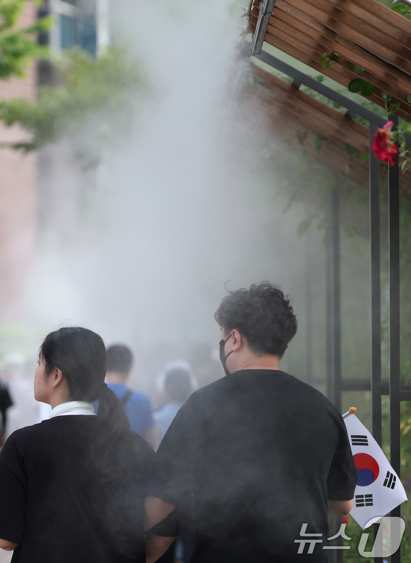 (서울=뉴스1) 오대일 기자 = 광복절 연휴 둘째 날인 16일 전국 대부분 지역에 폭염특보가 발효된 가운데 서울 중구 서울광장에서 태극기를 든 시민들이 쿨링포그를 지나며 더위를 식 …