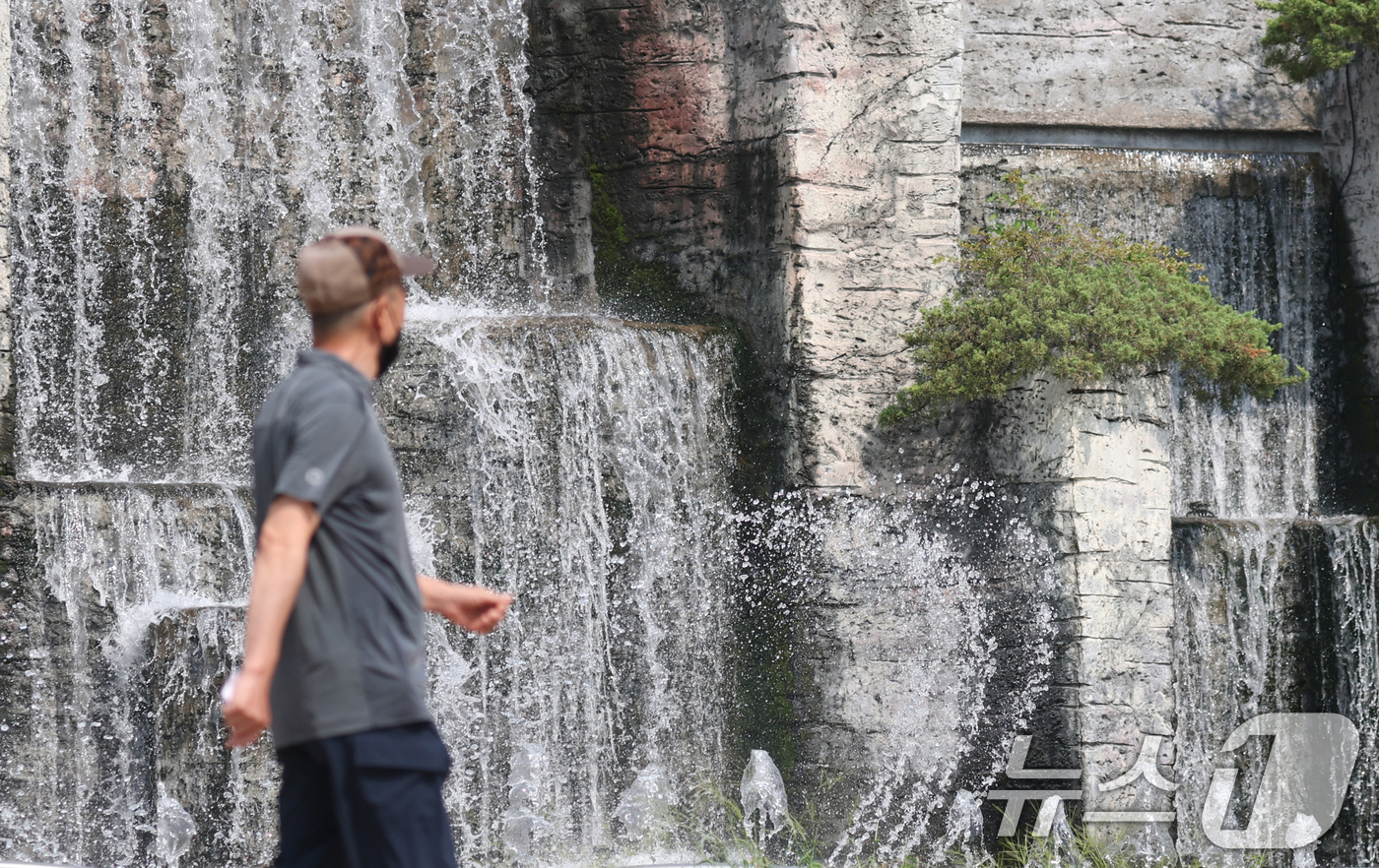 (오산=뉴스1) 김영운 기자 = 전국 대부분 지역에 폭염 경보나 주의보가 이어지고 있는 가운데 18일 오후 경기 오산시 수청공원에서 시민들이 시원하게 쏟아지는 폭포 앞으로 지나가고 …