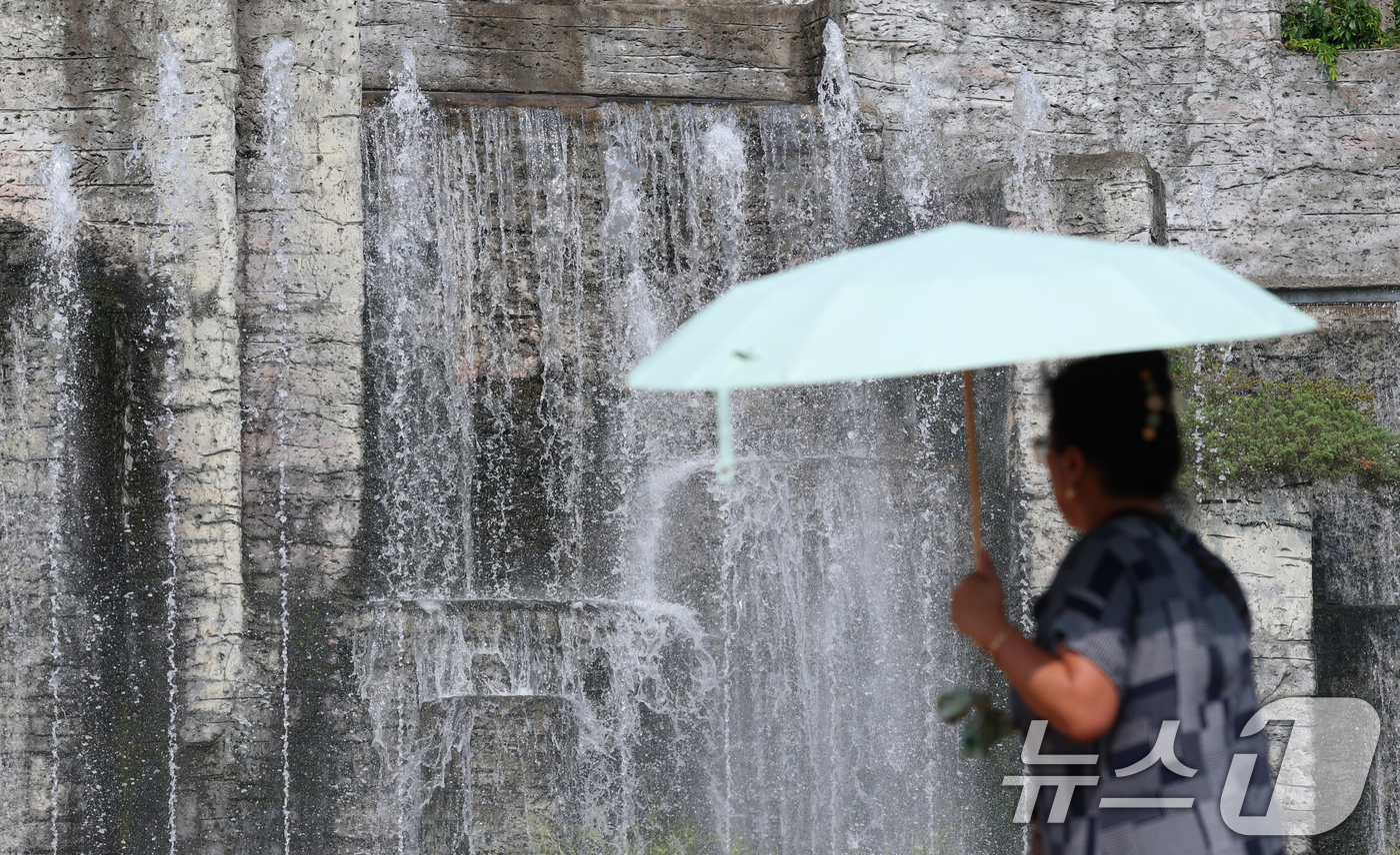 (오산=뉴스1) 김영운 기자 = 전국 대부분 지역에 폭염 경보나 주의보가 이어지고 있는 가운데 18일 오후 경기 오산시 수청공원에서 시민들이 시원하게 쏟아지는 폭포 앞으로 지나가고 …