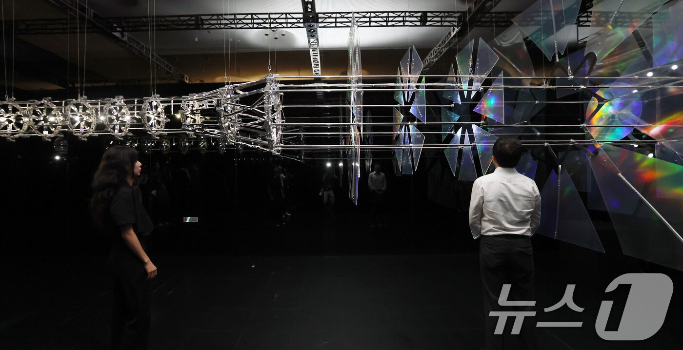 본문 이미지 - 19일 서울 동대문구 동대문디자인플라자(DDP)에서 열린 국가유산 활용 디지털 콘텐츠 전시 '헤리티지: 더 퓨처 판타지' 언론 공개회에서 방문객들이 한국의 탑을 빛과 움직임으로 재해석한 키네틱 아티스트 김준수의 '영원의 축'을 관람하고 았다.  2025.8.19/뉴스1 ⓒ News1 오대일 기자