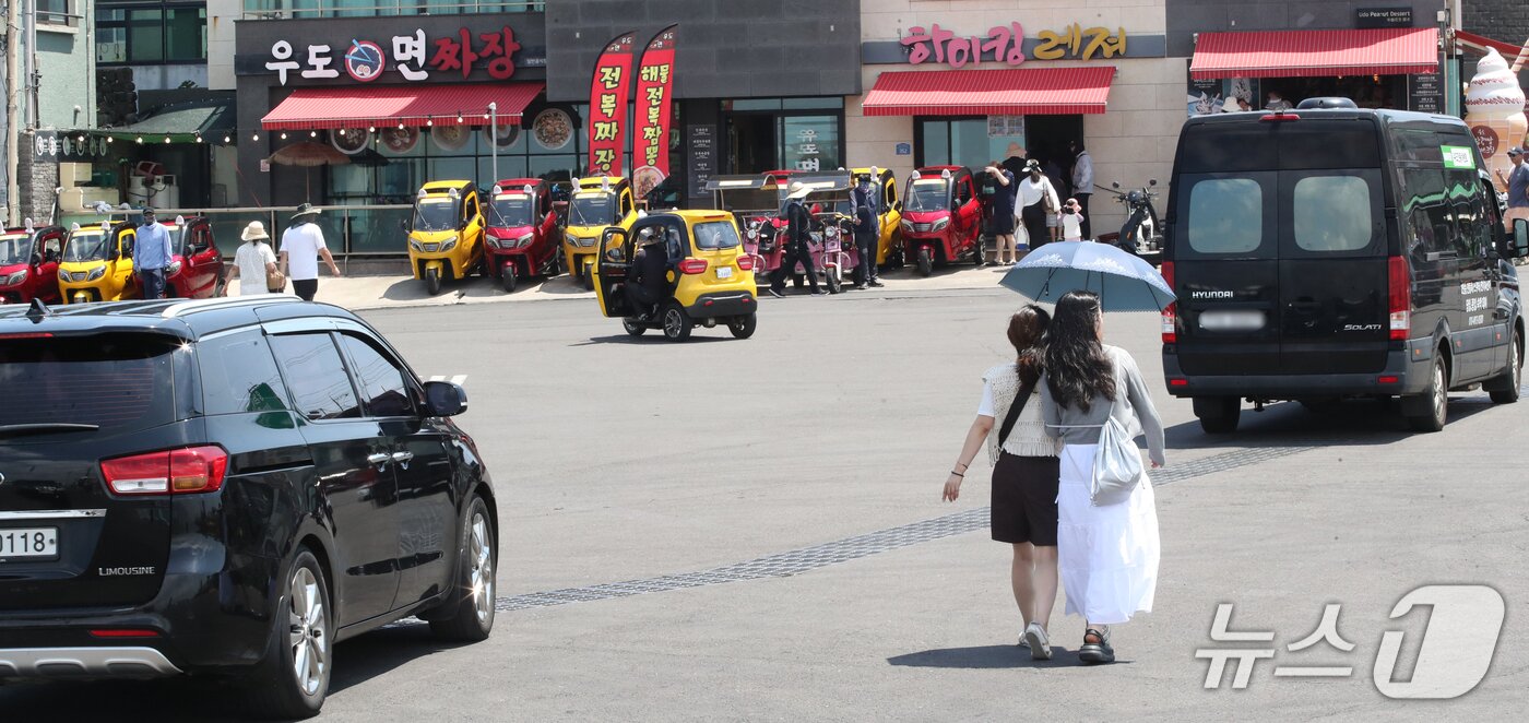 본문 이미지 - 지난 1일 오전 우도 하우목동항 앞 교차로가 차량과 보행자, 이륜차로 혼잡한 모습을 보이고 있다.