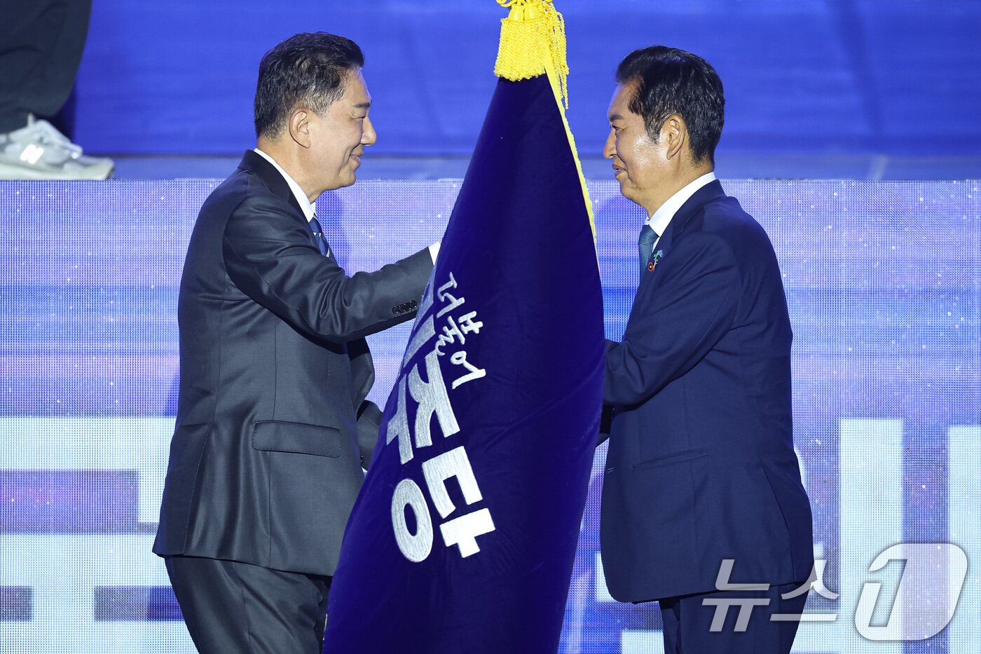 본문 이미지 - 정청래 더불어민주당 신임 당대표가 2일 경기 고양시 킨텍스에서 열린 제2차 임시전국당원대회에서 김병기 원내대표로 부터 당기를 이양받고 있다. 2025.8.2/뉴스1 ⓒ News1 유승관 기자