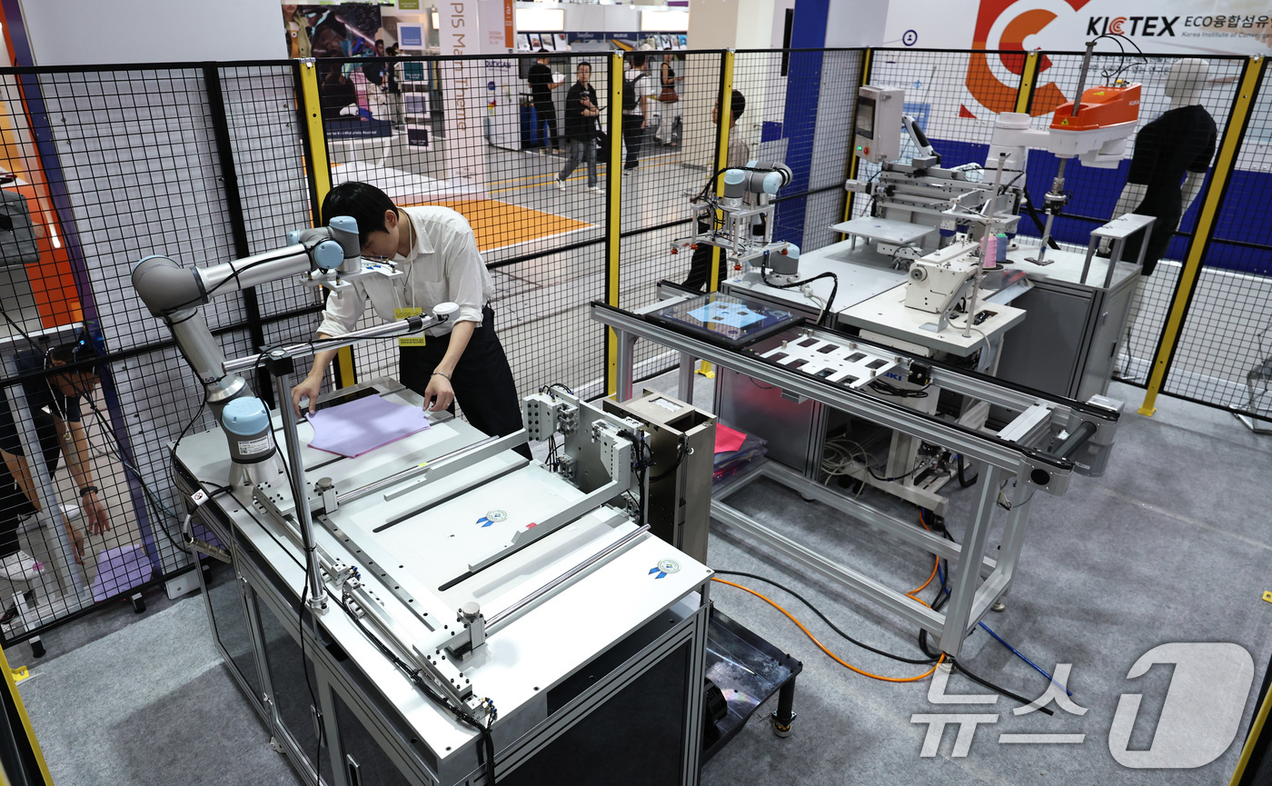 (서울=뉴스1) 구윤성 기자 = 20일 서울 강남구 코엑스에서 열린 '2025 대한민국 섬유교역전(프리뷰 인 서울 2025)에서 참관객들이 로봇기반 자동봉제시스템을 활용한 마이크로 …