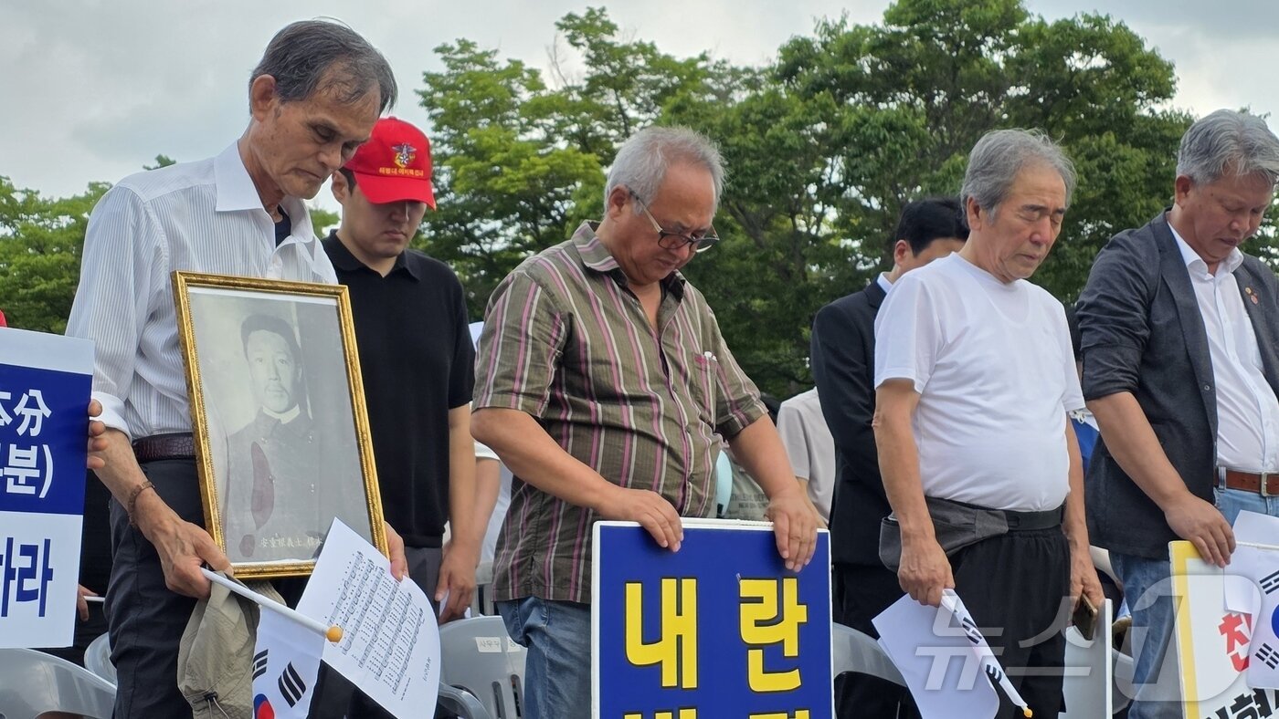 본문 이미지 - 23일 독립기념관 겨레의 마루에서 열린 김형석 관장 퇴진 촉구 집회에서 독립운동가 후손이 안중근 의사의 사진을 품에 안고 묵념하고 있다. 2025.8.23/뉴스1 ⓒ News1 이시우 기자