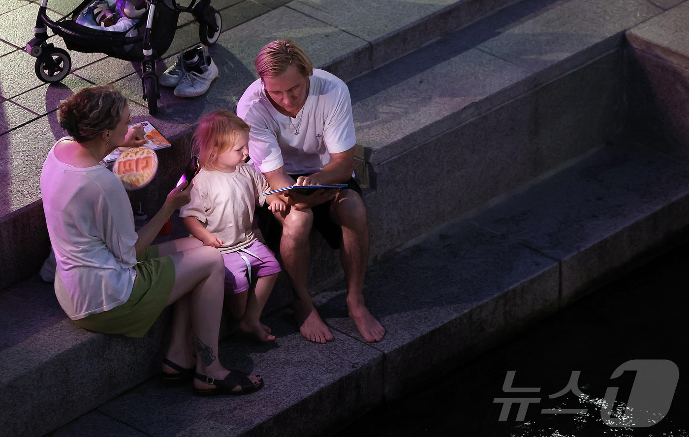 (서울=뉴스1) 김진환 기자 = 열대야가 이어지고 있는 24일 저녁 서울 중구 청계천을 찾은 외국인 관광객들이 더위를 식히고 있다. 2025.8.24/뉴스1