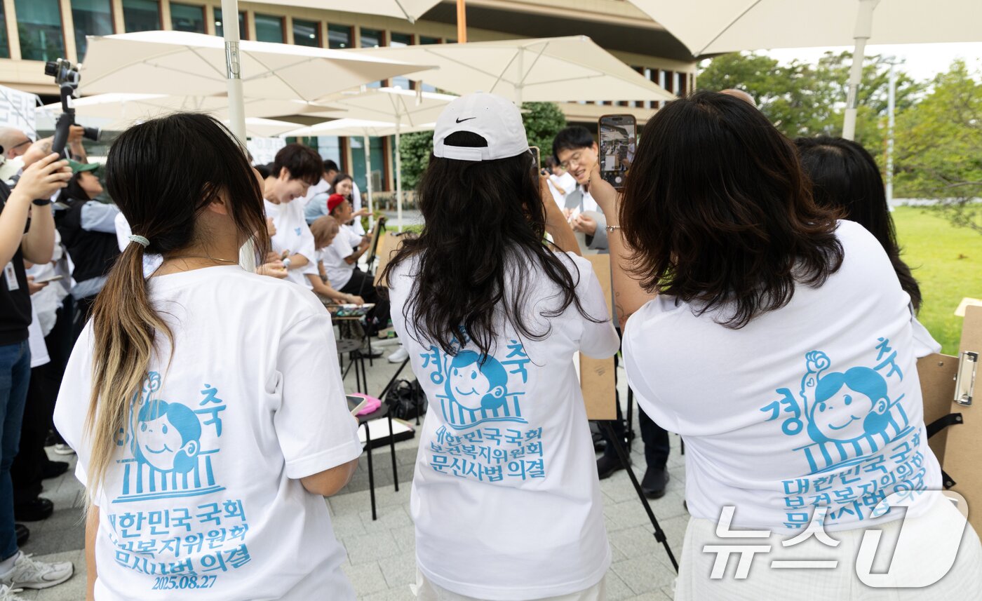 본문 이미지 - 27일 서울 여의도 국회 소통관 앞에서 타투이스트들이 보건복지위원회 문신사법 의결을 축하하며 박주민 위원장의 사진을 찍고 있다. 2025.8.27/뉴스1 ⓒ News1 이승배 기자