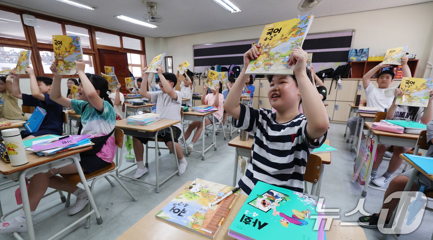 본문 이미지 - 5일 오전 여름방학을 마치고 개학한 경기 수원시 영통구 잠원초등학교에서 학생들이 새학기 교과서를 들어보이고 있다. 2025.8.5/뉴스1 ⓒ News1 김영운 기자