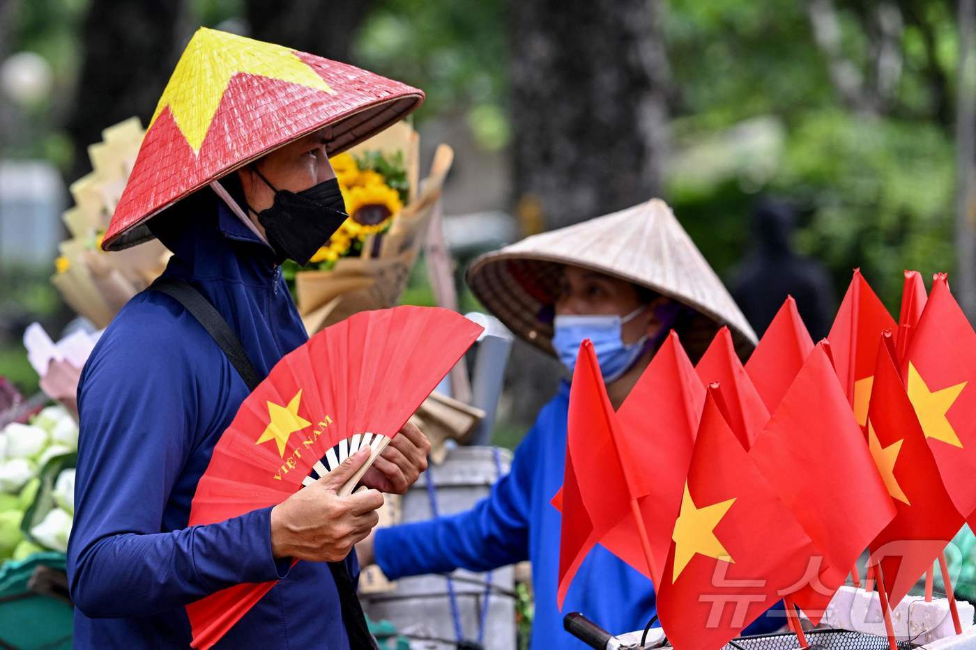 (하노이 AFP=뉴스1) 권영미 기자 = 5일 베트남 하노이에서 한 거리 상인이 작은 베트남 국기를 진열해 놓은 옆에서 부채질을 하며 더위를 식히고 있다. 이날 베트남 북부 지역은 …