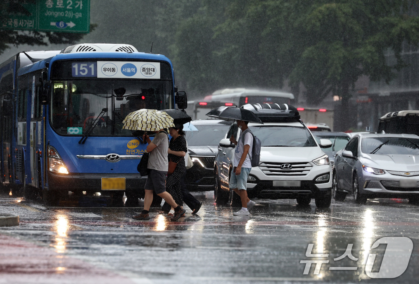 (서울=뉴스1) 구윤성 기자 = 서울 등 수도권과 충청지역에 호우 예비특보가 내려진 6일 오후 서울 종로 거리에서 우산을 쓴 시민들이 전조등을 켠 차량 앞을 지나고 있다. 2025 …