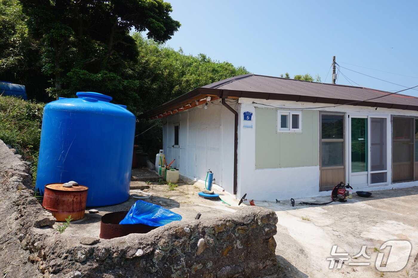 본문 이미지 - 물이 귀한 모도에서는 집집마다 커다란 물통&#40;왼쪽 파란색 통&#41; 설치가 생활의 필수조건이다. 2025.8.8/뉴스1 ⓒ News1 조영석 기자 