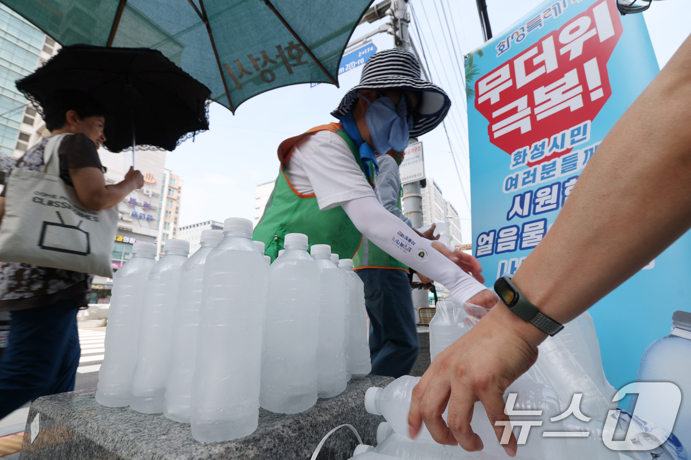 (화성=뉴스1) 김영운 기자 = 말복을 하루 앞둔 8일 경기 화성시의 한 거리에서 화성시 자율방재단이 시민들에게 얼음물을 나눠주고 있다.화성시의 얼음물 나눔 사업은 폭염이 누그러지 …