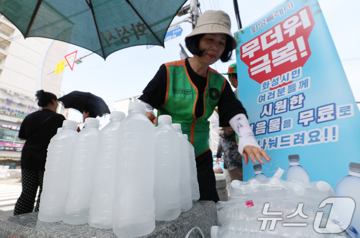 (화성=뉴스1) 김영운 기자 = 말복을 하루 앞둔 8일 경기 화성시의 한 거리에서 화성시 자율방재단이 시민들에게 얼음물을 나눠주고 있다.화성시의 얼음물 나눔 사업은 폭염이 누그러지 …