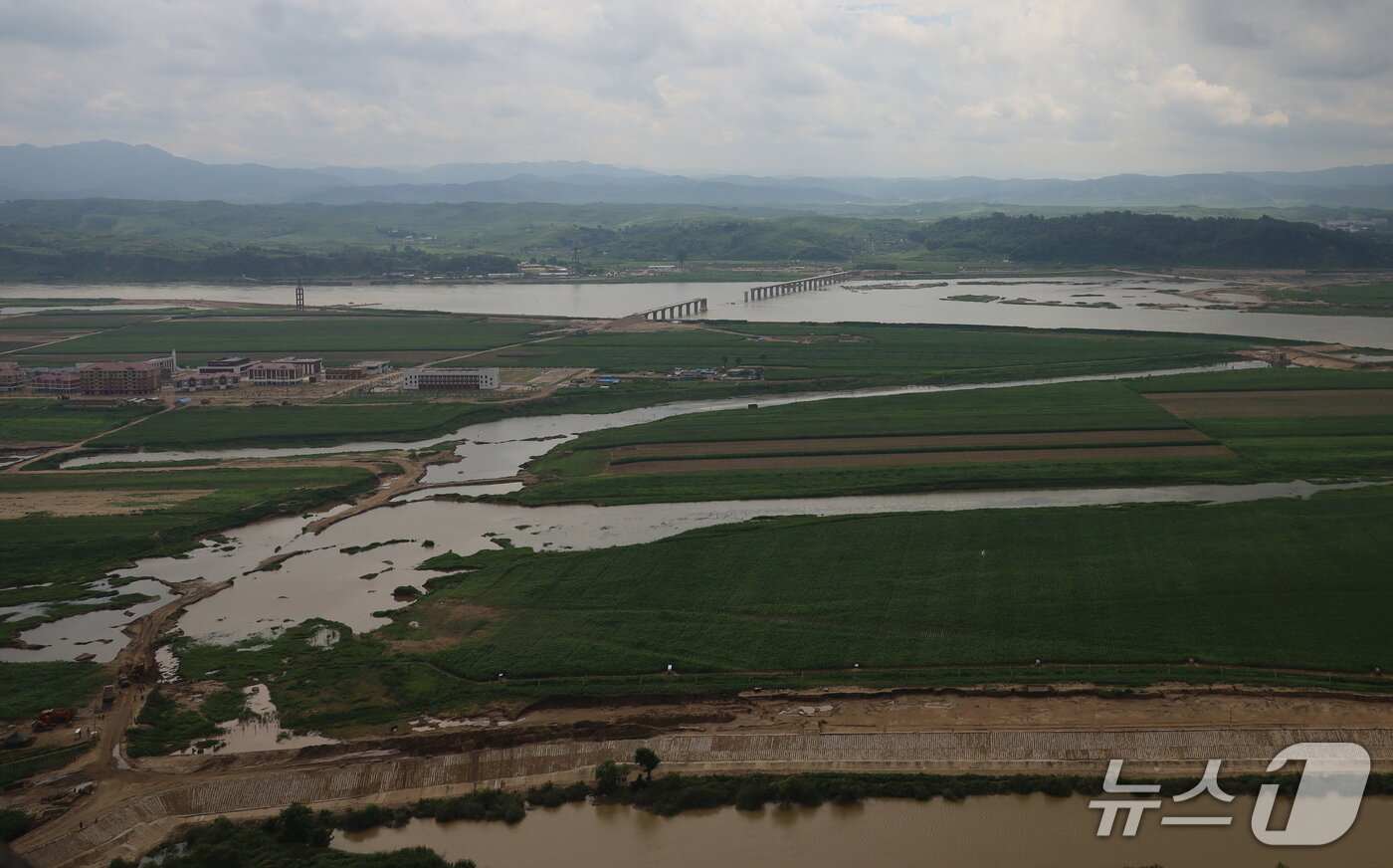 본문 이미지 - 중국 랴오닝성 단둥시 후산에서 본 어적도 전경. 지난해 홍수에 파괴된 주택들이 현대적으로 복구되었고, 어적도와 의주를 잇는 새 다리 건설과 제방 공사가 한창 진행 중이다. &#40;평화경제연구소 제공&#41;