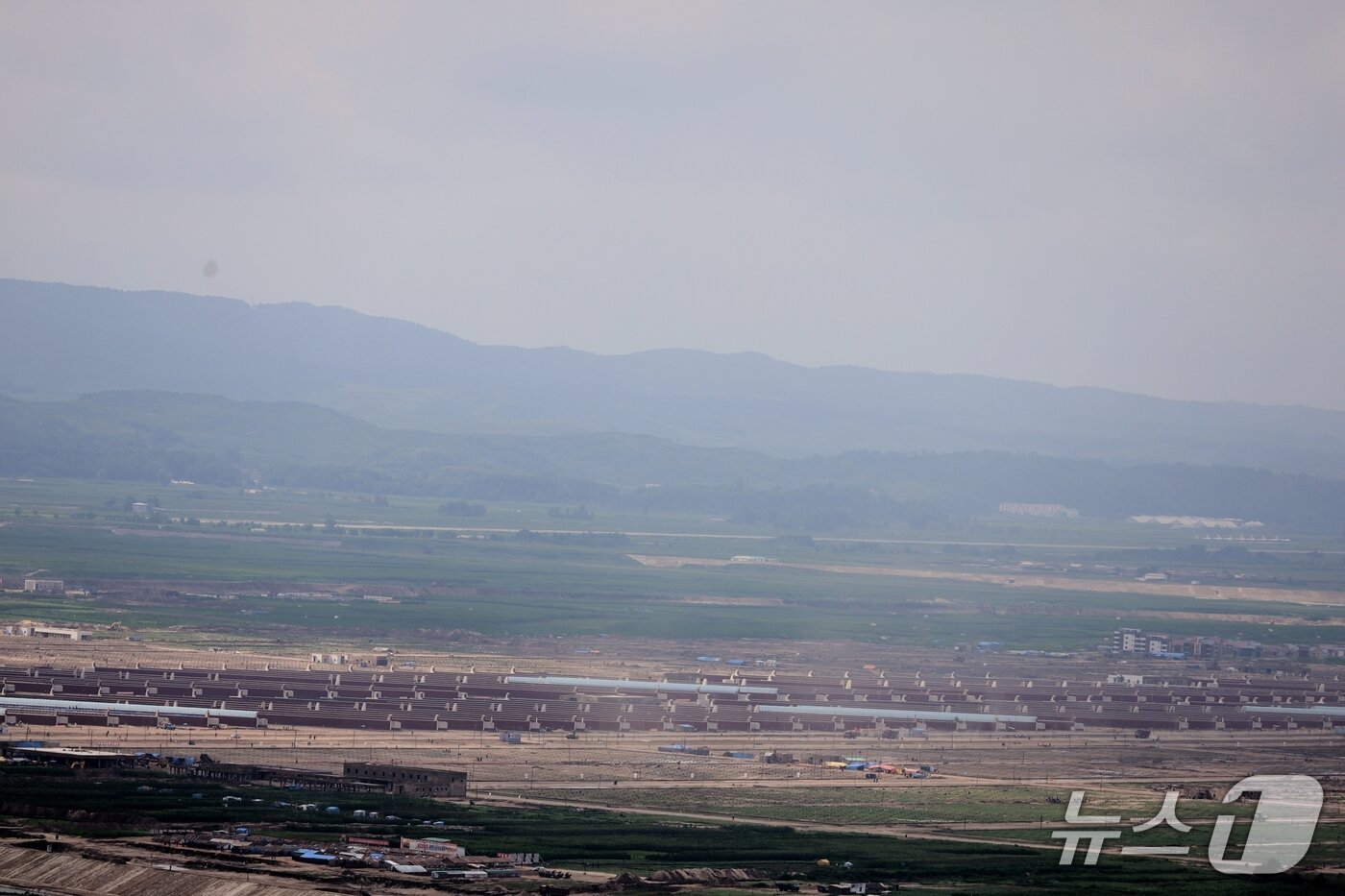 본문 이미지 - 중국 랴오닝성 단둥시 후산에서 본 의주군 서호리의 대규모 남새온실농장 건설 현장 모습. 의주군 서호리에서 신의주시 위화도까지 여의도와 비슷한 면적으로 조성되는 남새온실농장은 현재 외관공사를 마치고 내부시설과 주변 기반시설 공사가 이뤄지고 있다. &#40;평화경제연구소 제공&#41;