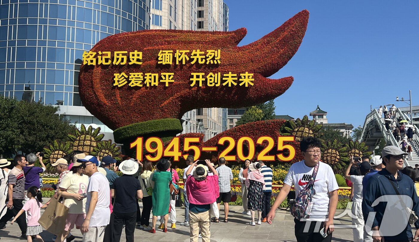 본문 이미지 - 중국의 항일전쟁 및 세계 반파시스트 전쟁&#40;제2차 세계대전&#41; 승리 80주년&#40;전승절&#41; 기념 열병식을 이틀 앞둔 1일 오전 중국 베이징 천안문 인근 거리에 설치된 꽃 조형물 앞에서 행인들이 기념 사진을 찍고 있다. 2025.9.1/뉴스1 ⓒ News1 박정호 기자