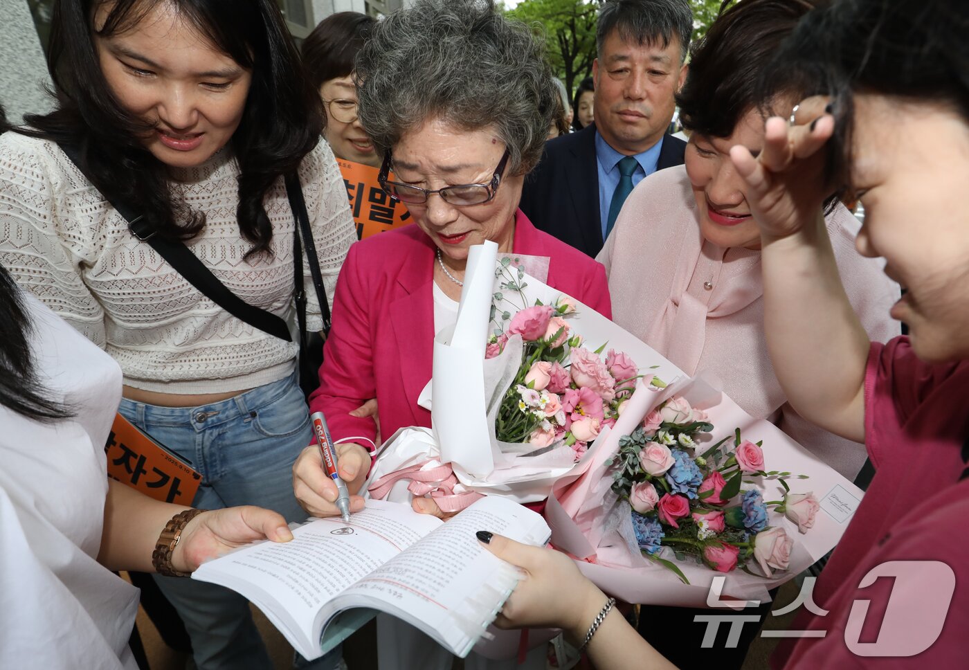 본문 이미지 - 61년 전 성폭행범 혀를 깨물어 집행유예 확정판결을 받았던 최말자 씨가 10일 오후 부산 연제구 부산지방법원에서 열린 재심 선고공판에서 무죄를 선고받은 뒤 법정을 나서며 한 시민의 요청에 사인을 해주고 있다.  2025.9.10/뉴스1 ⓒ News1 윤일지 기자