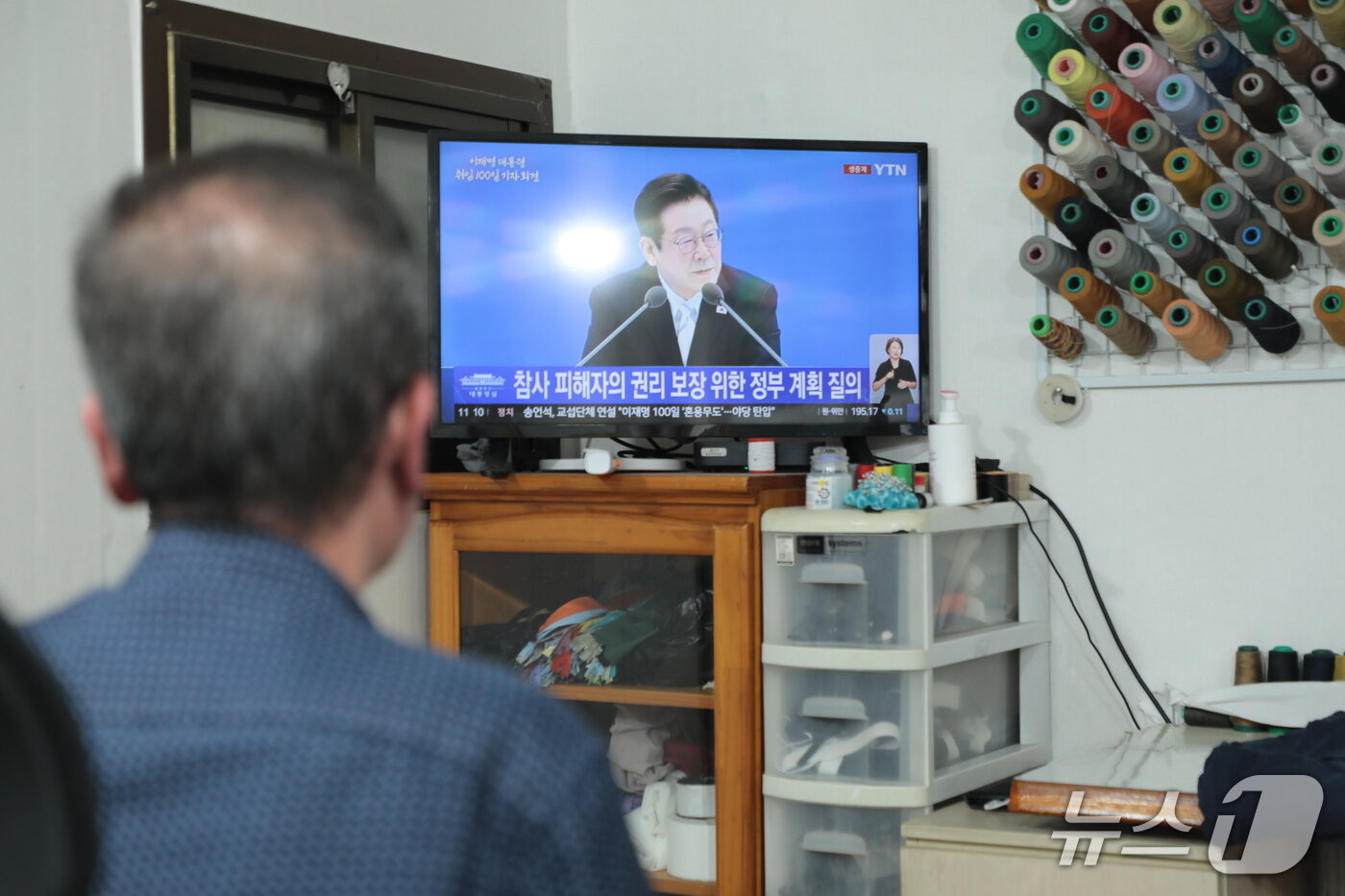 본문 이미지 - 울산 남구의 한 옷 수선점에서 한 상인이 생중계로 이재명 대통령의 취임 100일 기념 기자회견을 시청하고 있다.2025.9.11./ⓒ 뉴스1 김세은 기자
