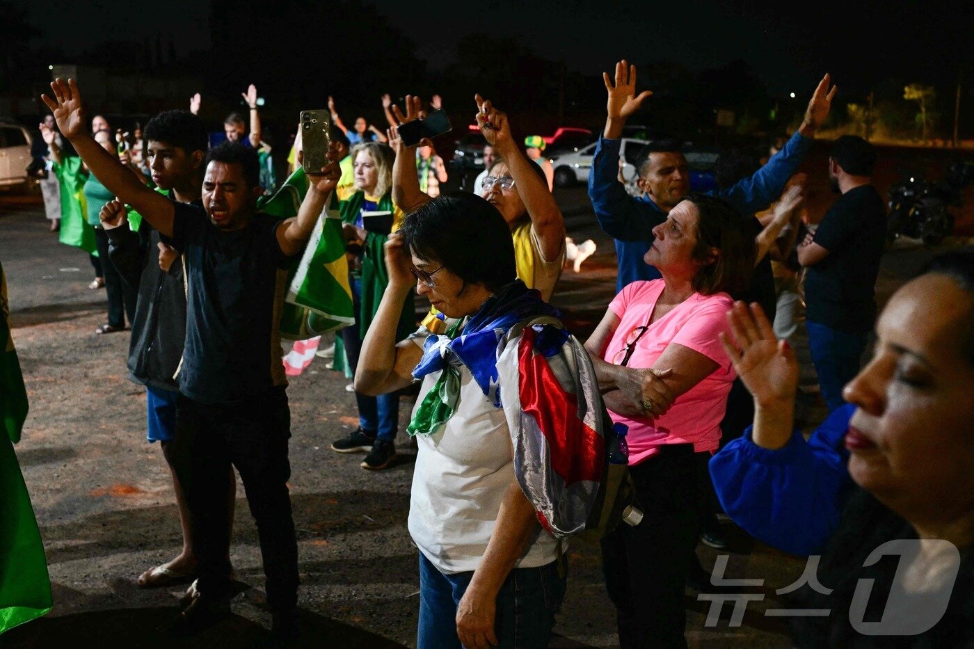 본문 이미지 - 11일&#40;현지시간&#41; 브라질리아에 위치한 자이르 보우소나루 전 대통령의 자택 인근에서 지지자들이 기도를 올리고 있다. 브라질 연방대법원은 이날 쿠데타 모의 혐의로 보우소나루 전 대통령에게 징역 27년을 선고했다. 2025.09.11ⓒ AFP=뉴스1