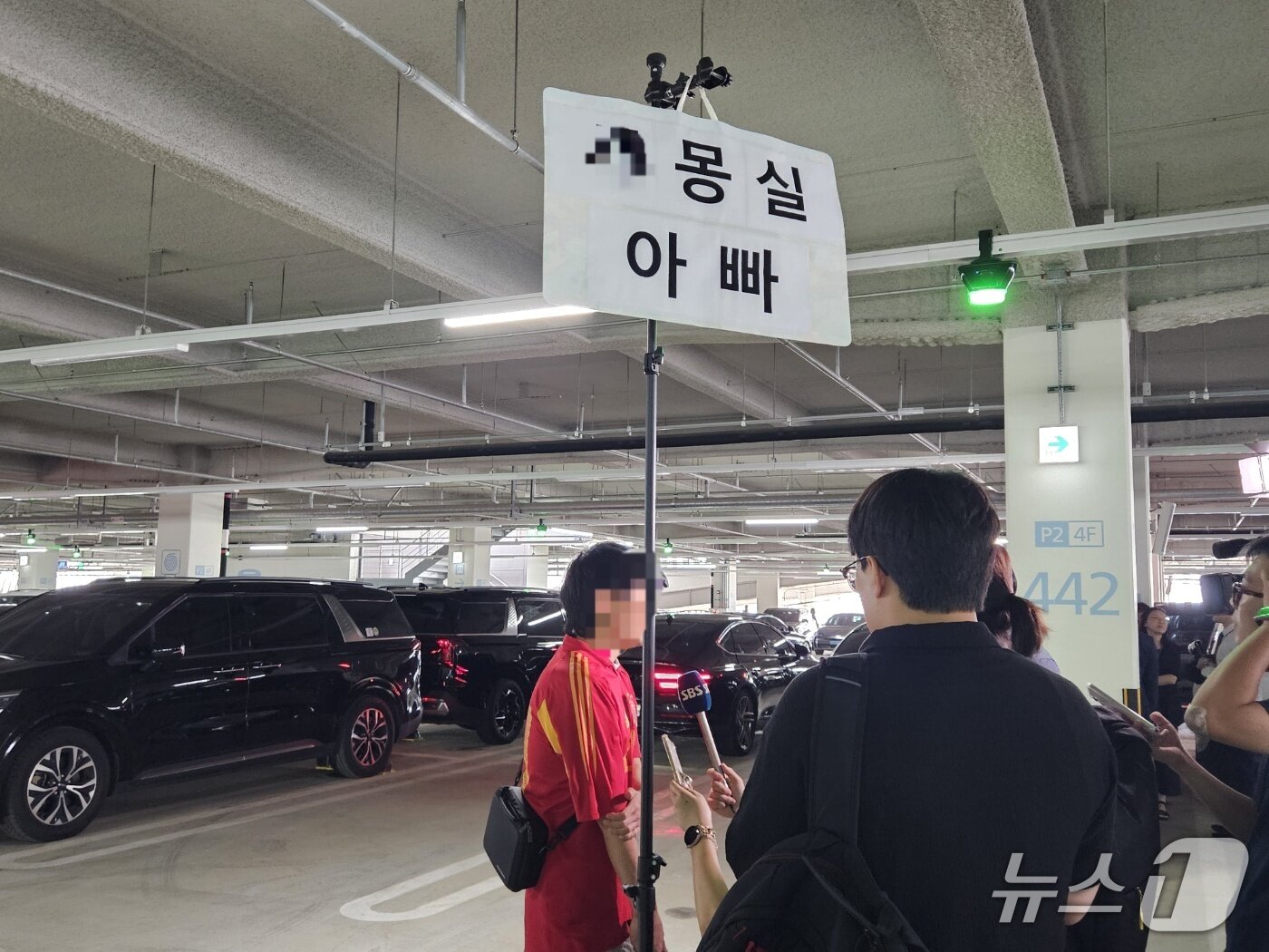 본문 이미지 - 12일 미국에 구금됐다가 풀려난 한국인 직원의 귀국을 기다리는 가족이 반려견 이름이 적힌 피켓을 들고 언론 인터뷰를 하고 있다. 2025.09.12/ⓒ 뉴스1 윤주현 기자