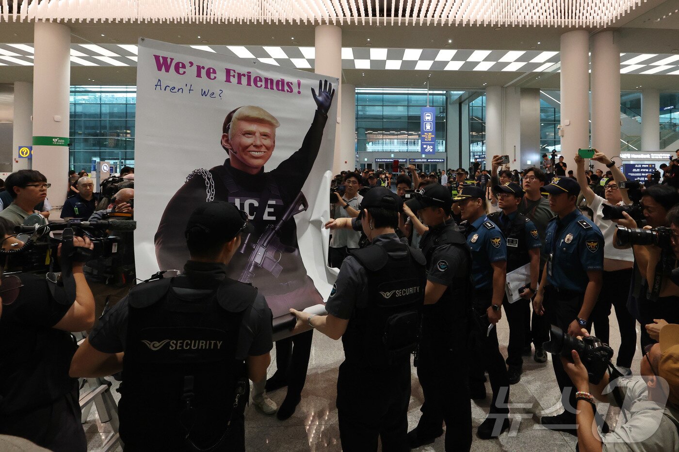 본문 이미지 - 미국 이민당국에 의해 조지아주에 구금됐던 한국인 근로자들이 귀국한 12일 인천국제공항 제2여객터미널 입국장에서 도널드 트럼프 미국대통령 얼굴 배너를 든 시민단체가 시위하고 있다. (공동취재) 2025.9.12/뉴스1 ⓒ News1 박지혜 기자