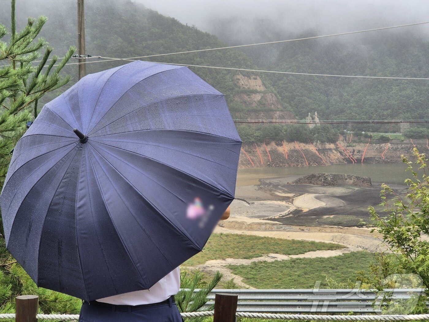 본문 이미지 - 극심한 가뭄을 겪고 있는 강원 강릉지역에 많은 비가 내린 13일 오전 우산을 쓴 시민이 마른 저수지에 내리는 단비를 바라보고 있다. 2025.9.13/뉴스1 ⓒ News1 윤왕근 기자