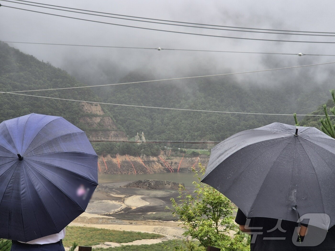 본문 이미지 - 극심한 가뭄을 겪고 있는 강원 강릉지역에 많은 비가 내린 지난 13일 오전 우산을 쓴 시민이 마른 저수지에 내리는 단비를 바라보고 있다. 2025.9.13/뉴스1 ⓒ News1 윤왕근 기자